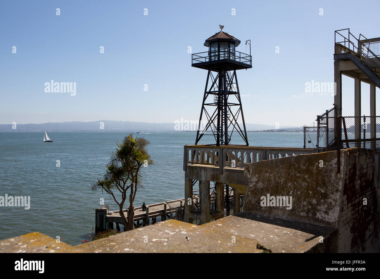 Une tour sur l'île d'Alcatraz, et une vue panoramique sur l'eau et d'un voilier au large. Banque D'Images