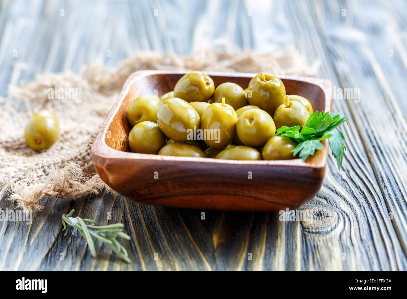 Les olives vertes et le persil dans un bol en bois. Banque D'Images