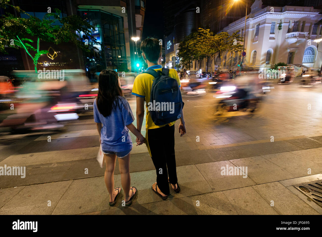 Couple en attente de traverser une rue à Ho Chi Minh City, Vietnam, Asie Banque D'Images