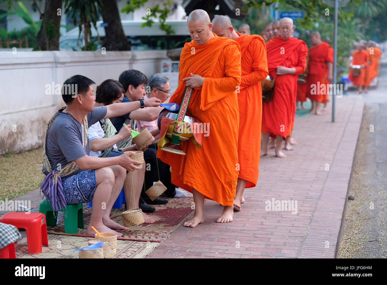 Procession de moines bouddhistes en robe orange à l'aube pour recueillir des dons dans les rues de Luang Prabang, Laos, Asie Banque D'Images
