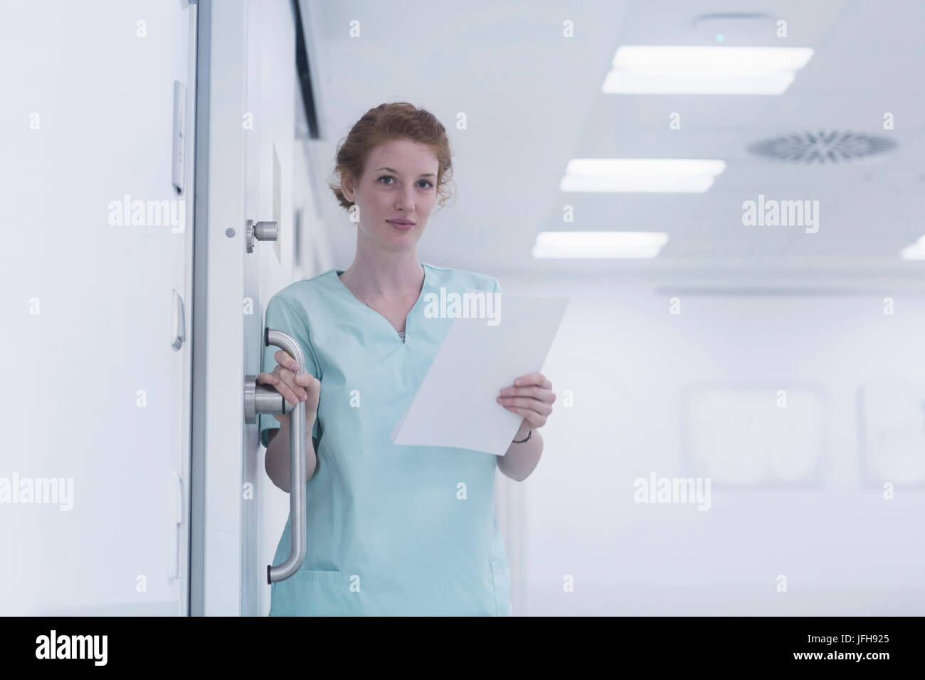 Portrait of nurse holding poignée de porte et des dossiers médicaux Banque D'Images