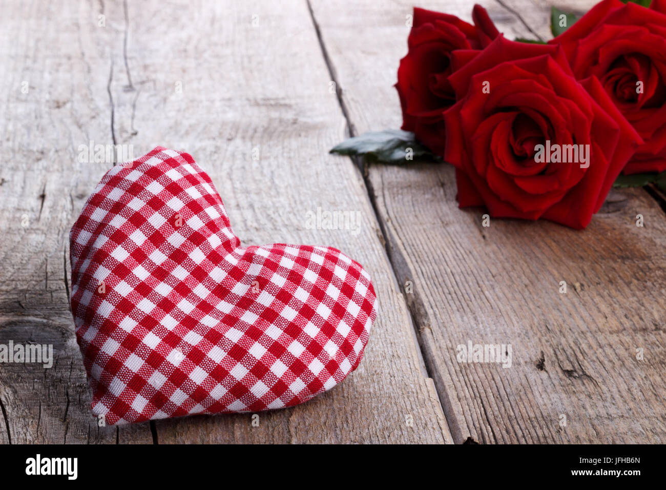 Roses rouges et un coeur sur fond de bois Banque D'Images