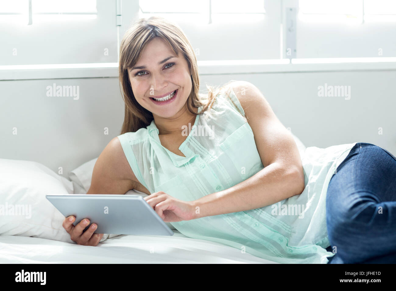 Belle femme smiling while sitting on bed Banque D'Images