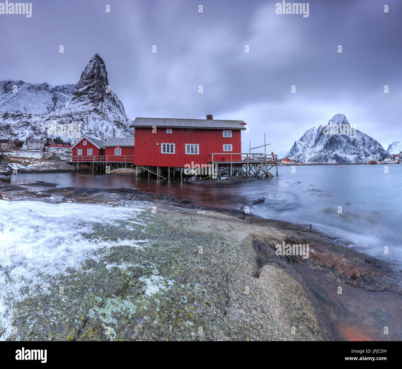 Maisons typiques en Reine rouge paysage avec sa mer froide et pics enneigés, Lofoten, Norvège Europe Banque D'Images