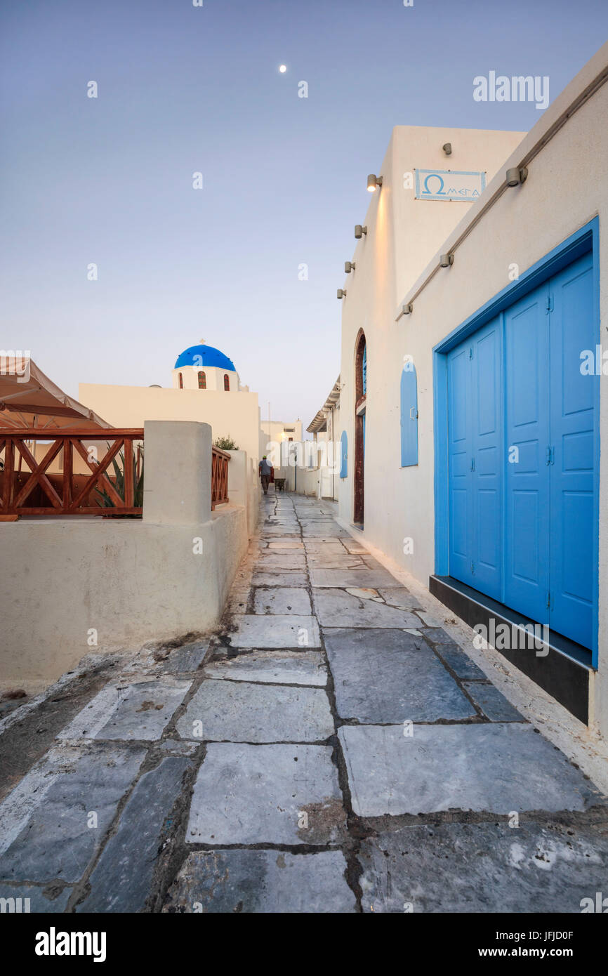 La lune au-dessus des maisons blanches et de dômes bleus des églises dans une ruelle étroite d'Oia Santorini Cyclades Grèce Europe Banque D'Images