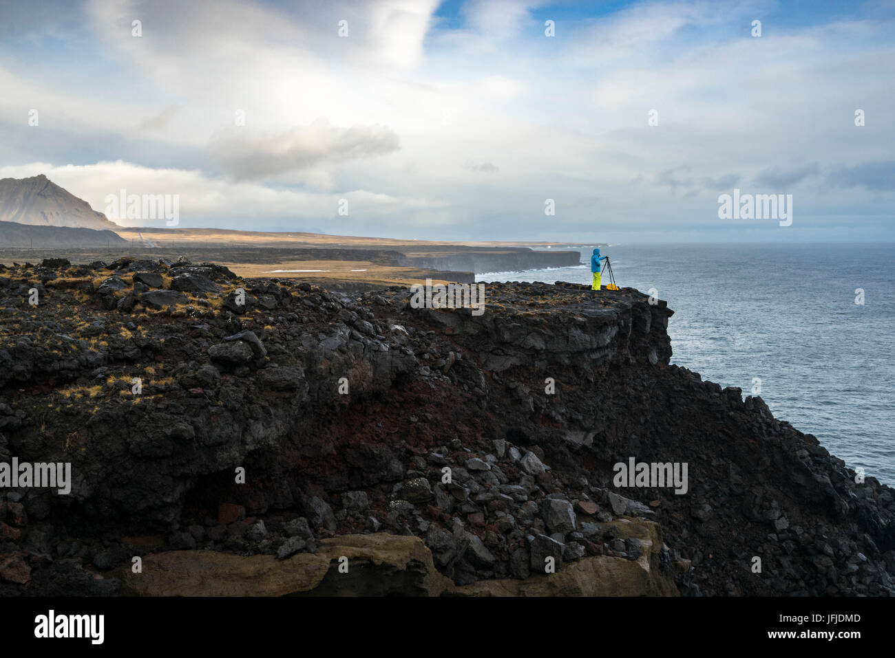 Un photographe prend des photos avec un trépied debout sur les falaises près de Londrangar, Snaefellsjoekull National Park, dans l'ouest de l'Islande, Europe Banque D'Images