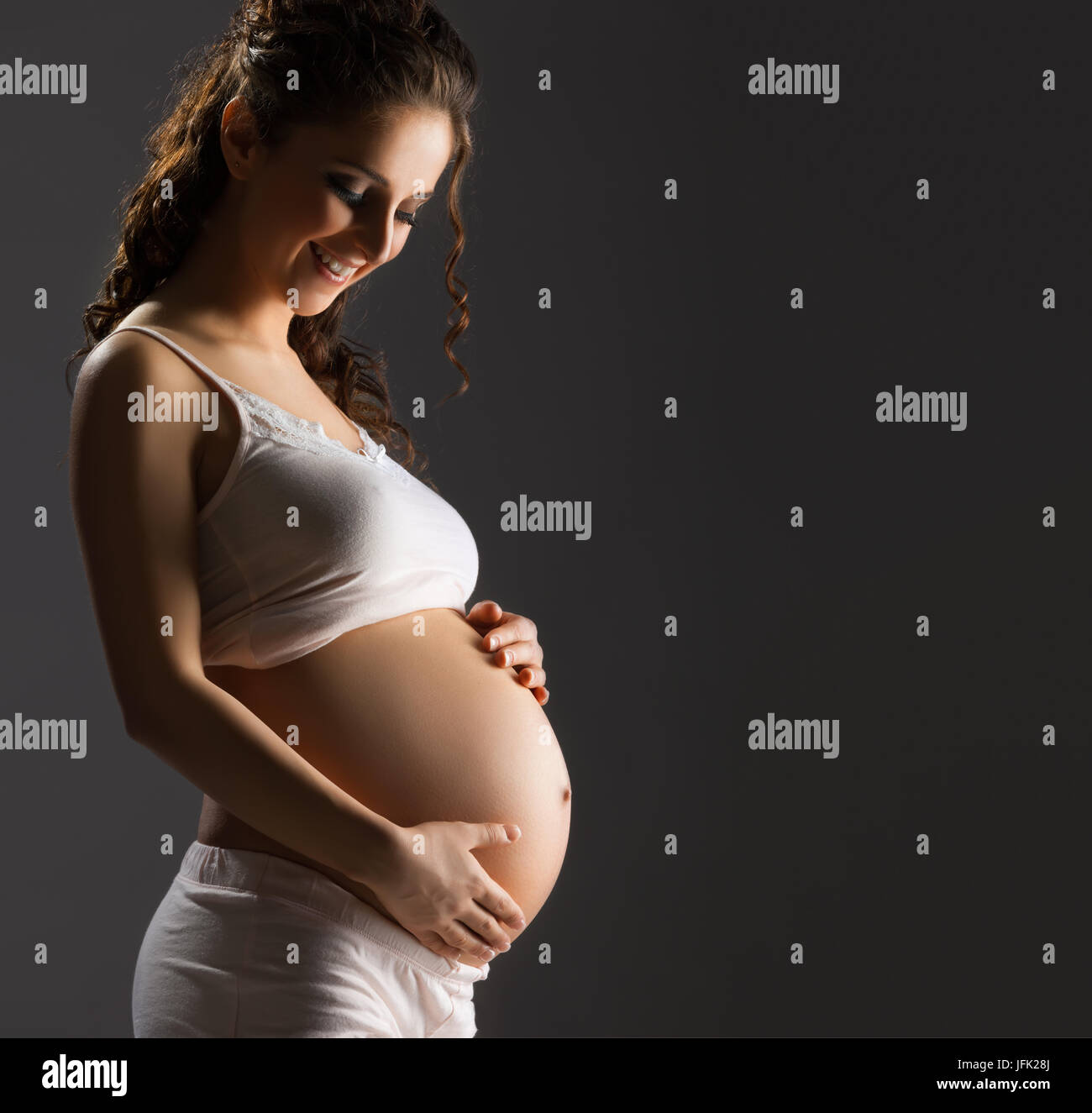 Caressant son ventre femme enceinte Banque D'Images