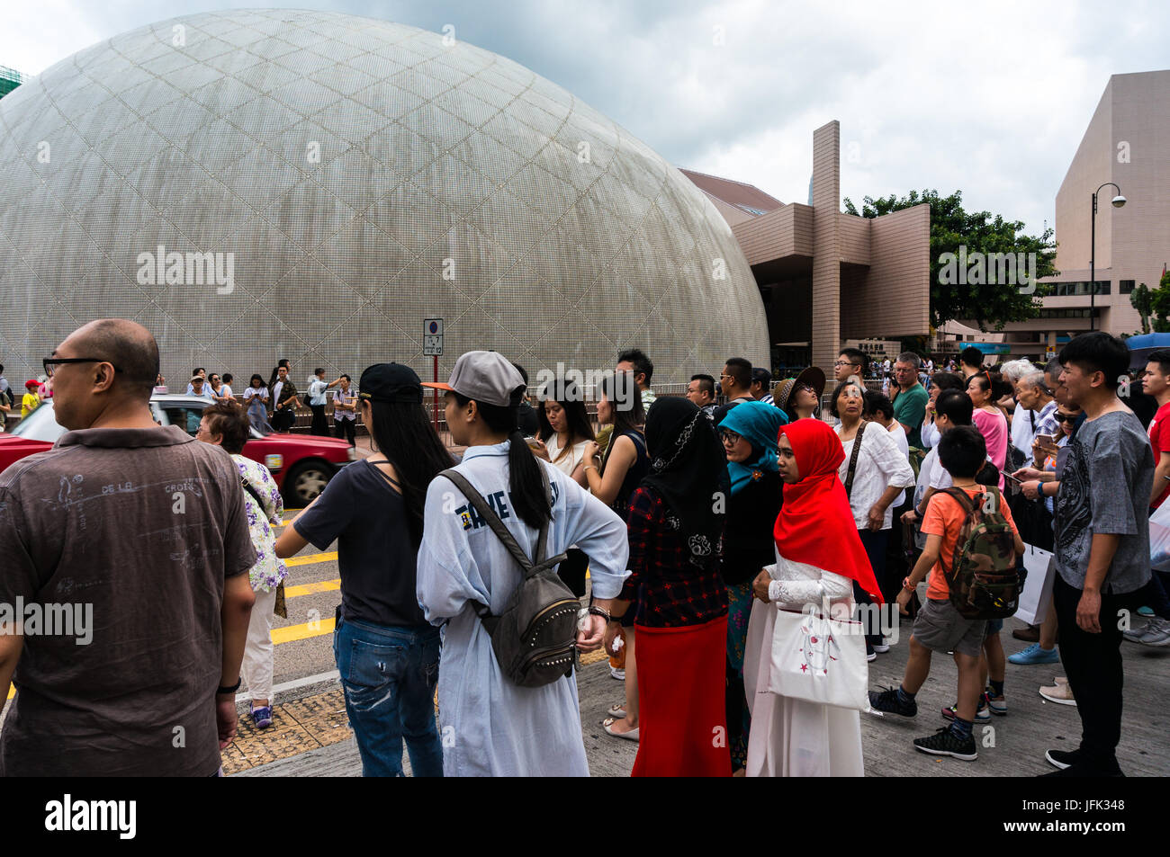 Touristes et habitants à Tsim Sha Tsui en attente à l'intersection de la rue croix de dome, Musée de l'espace de Hong Kong en arrière-plan Banque D'Images