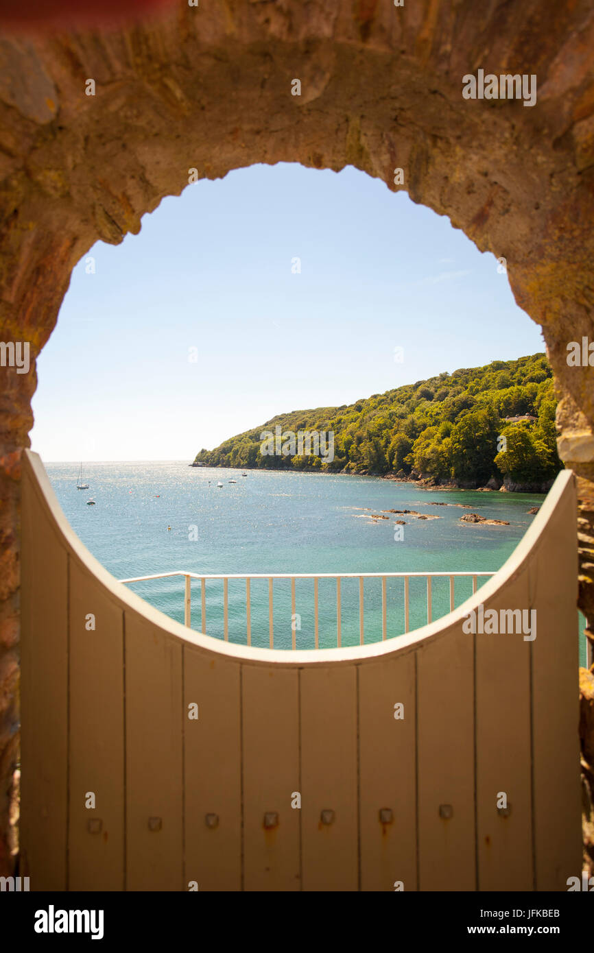 Une porte avec une belle vue sur la baie à Cawsand viewd à travers un mur et encadrée cirle barrière en bois, Cornwall, Angleterre Banque D'Images