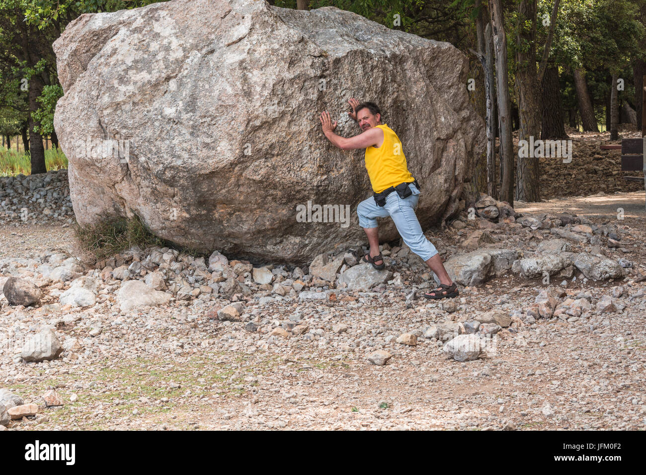 L'homme se tient devant un grand rocher. Tâche de faire face. Banque D'Images