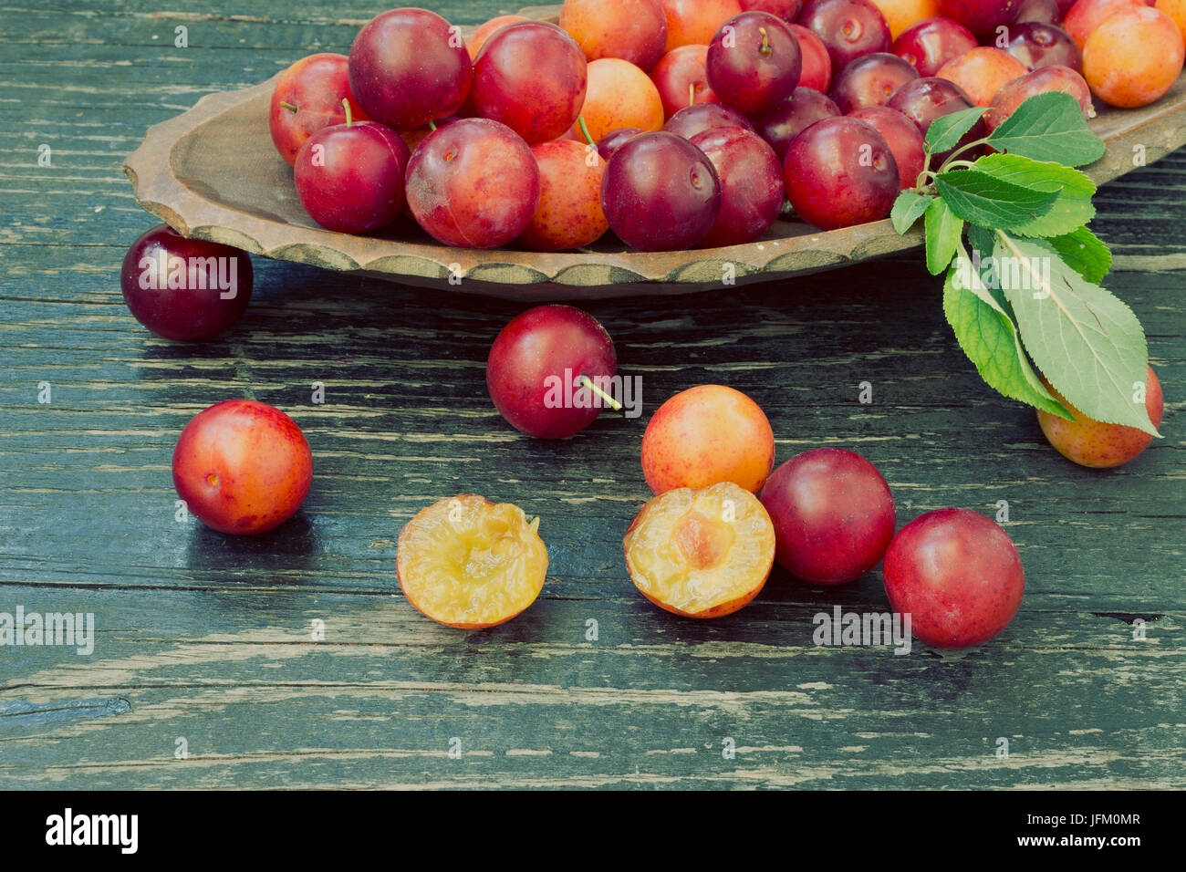 Les prunes mûres avec des tranches de fruits sur fond de bois - look vintage Banque D'Images
