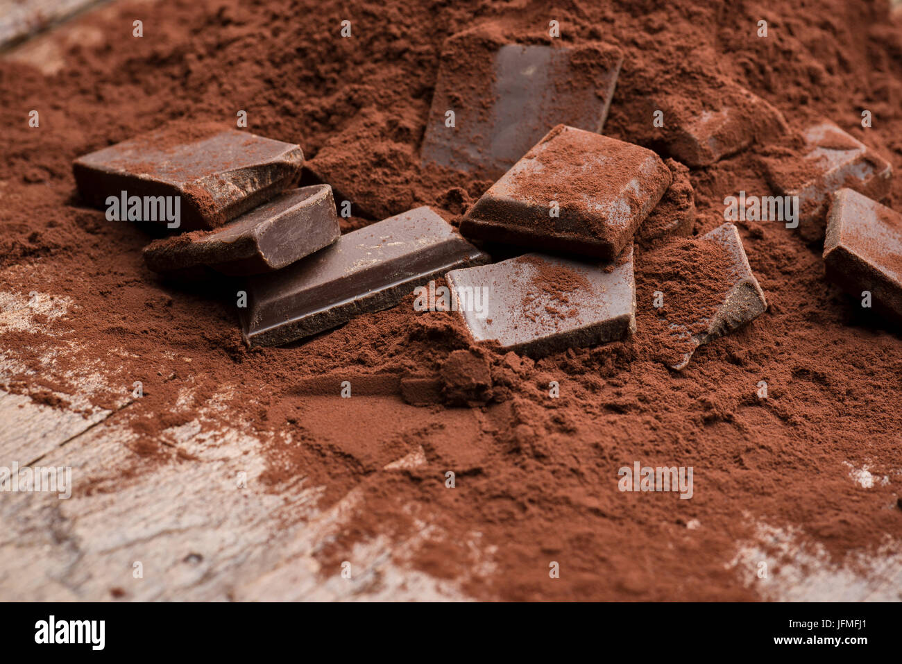 Tas de poudre de cacao avec du chocolat bloc sur table en bois Banque D'Images