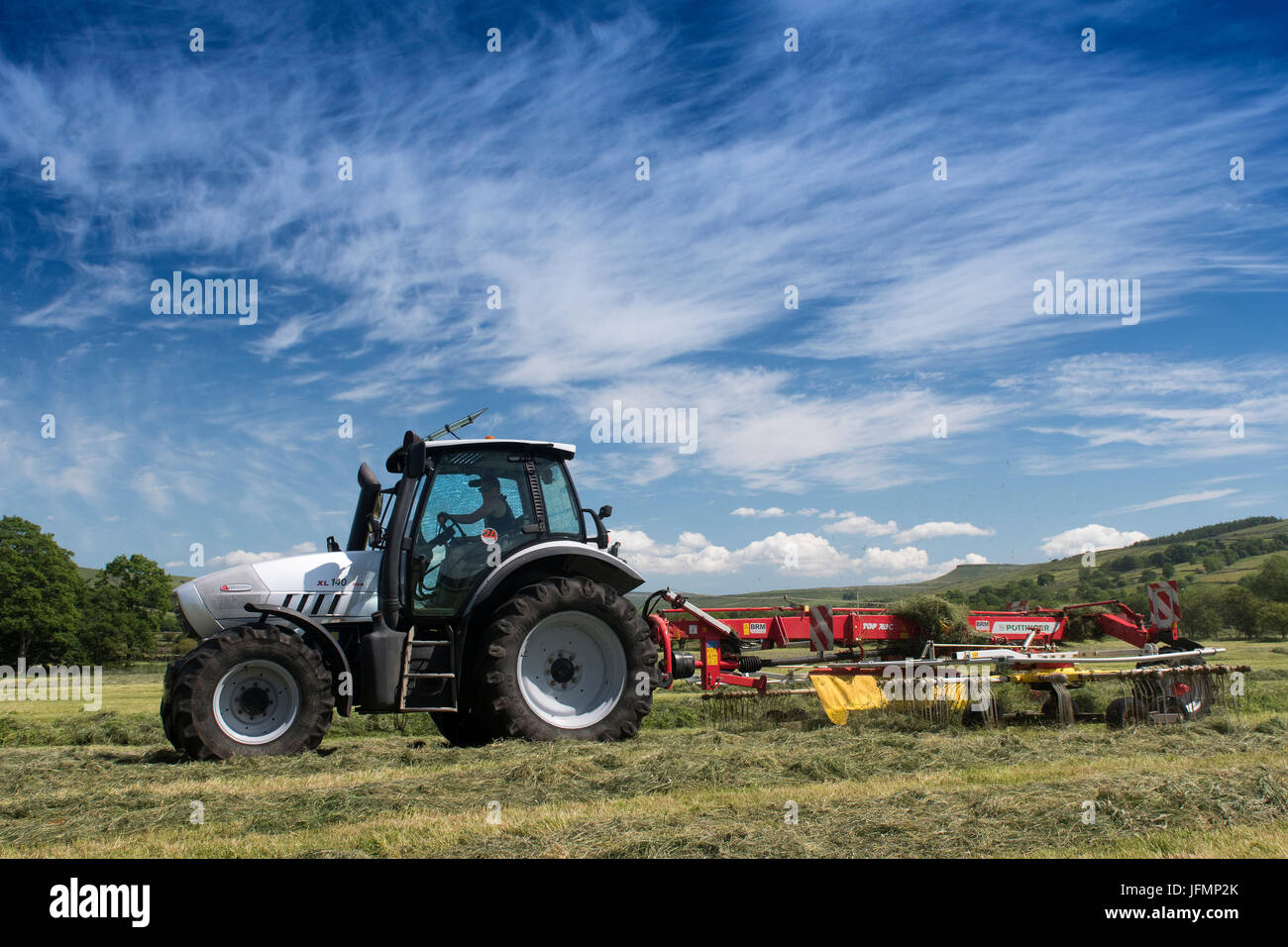 Pour l'ensilage d'herbe de l'aviron à l'aide d'un râteau Pottinger tiré par un tracteur Hurlimann, dans le Yorkshire Dales, au Royaume-Uni. Banque D'Images