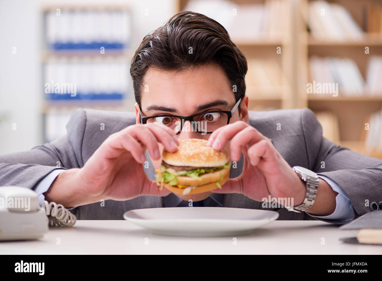 Faim funny businessman eating junk food sandwich Banque D'Images