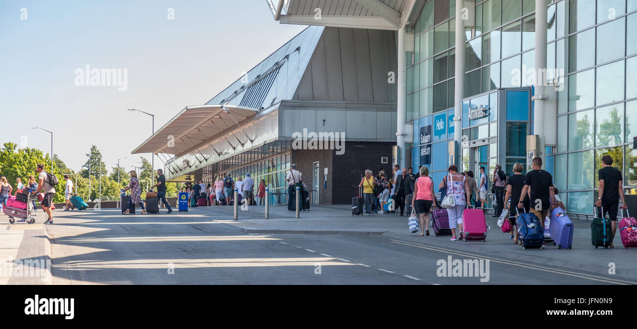 Les passagers aériens arrivant à l'aéroport de Birmingham, UK de quitter le terminal et de marcher jusqu'à la location de parcs, de taxis et des arrêts de bus. Banque D'Images