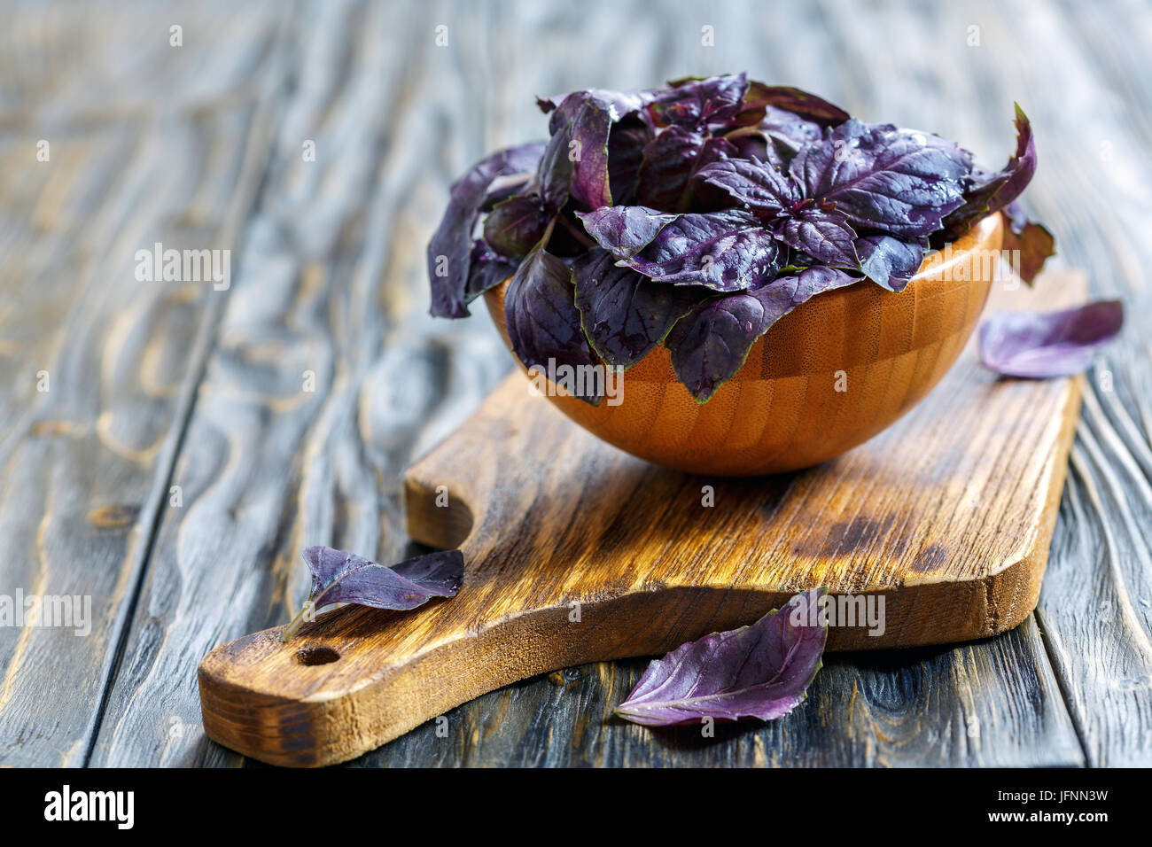 Bol en bois avec des feuilles de basilic pourpre c gouttes d'eau. Banque D'Images