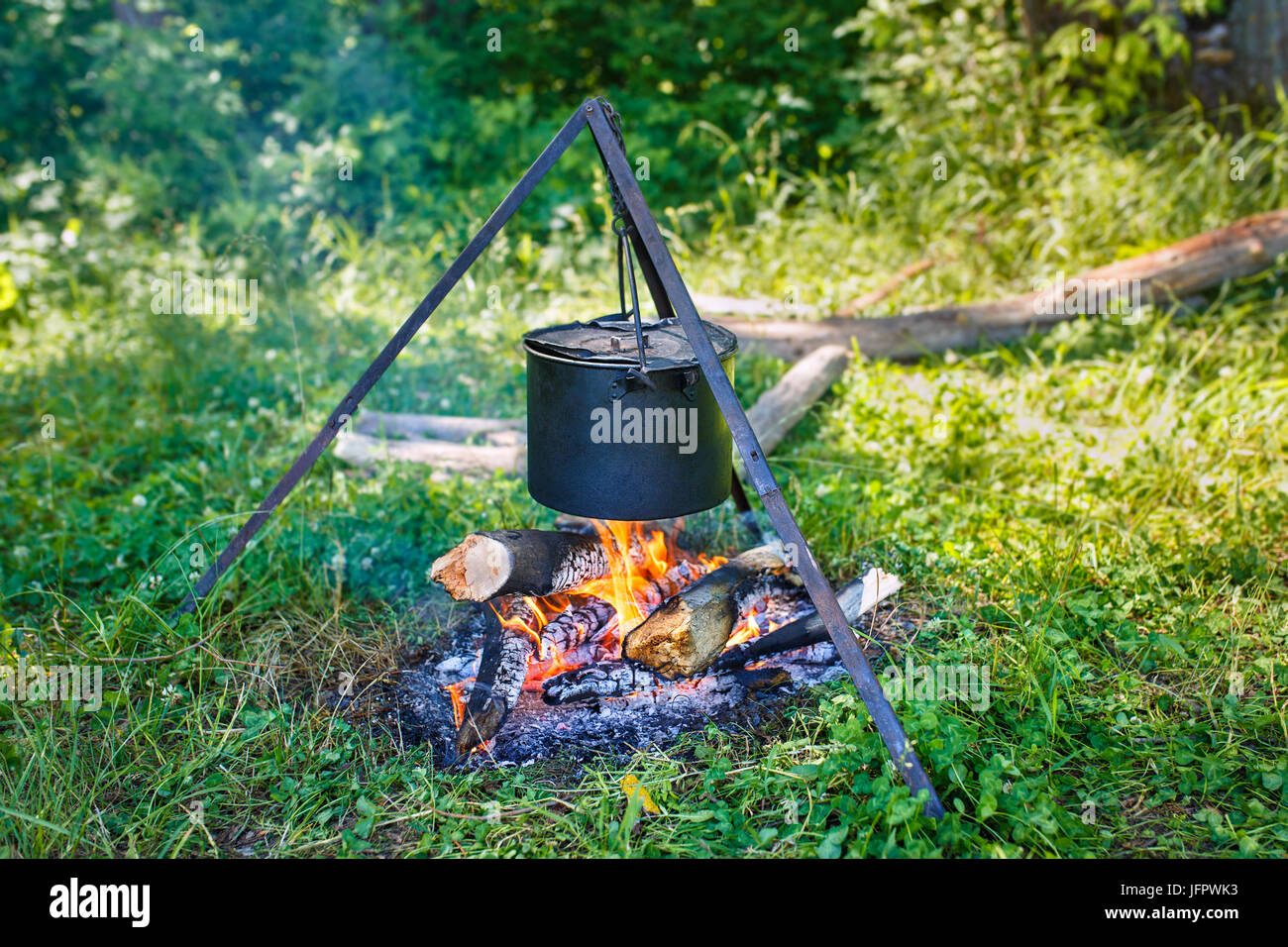 La cuisson des aliments au pieu à l'extérieur. Le camping, le pique-nique dans la nature, camp de la nourriture, de la randonnée et du tourisme voyage concept. Casserole sur le bûcher. De Camp. Électrique sur Banque D'Images