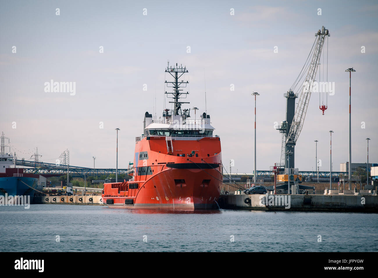 Navire de fret rouge en face des installations portuaires et de grues Banque D'Images