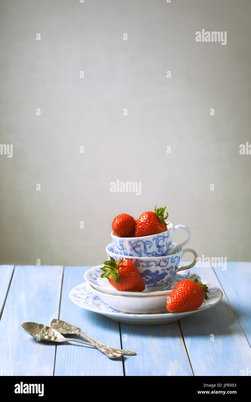 En fraise vintage tasse et soucoupes avec cuillères de sucre sur la table rustique Banque D'Images