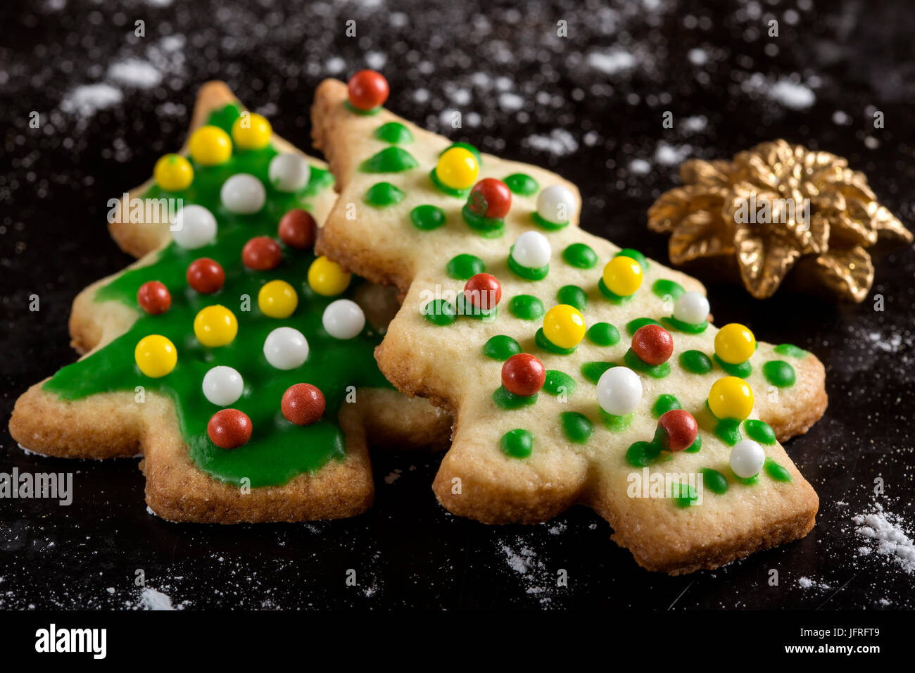 Les biscuits de Noël et d'épices en forme de sapin - Cuisine traditionnelle sur fond sombre avec du sucre en poudre Banque D'Images