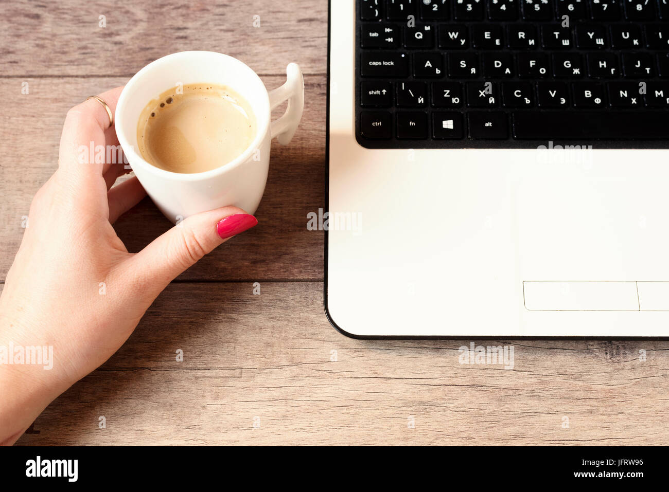 Femme working on laptop in cafe. Tasse de café blanc. Close up of a woman avec joints toriques et les ongles longs, peint avec laque rouge. En utilisant internet. H Banque D'Images