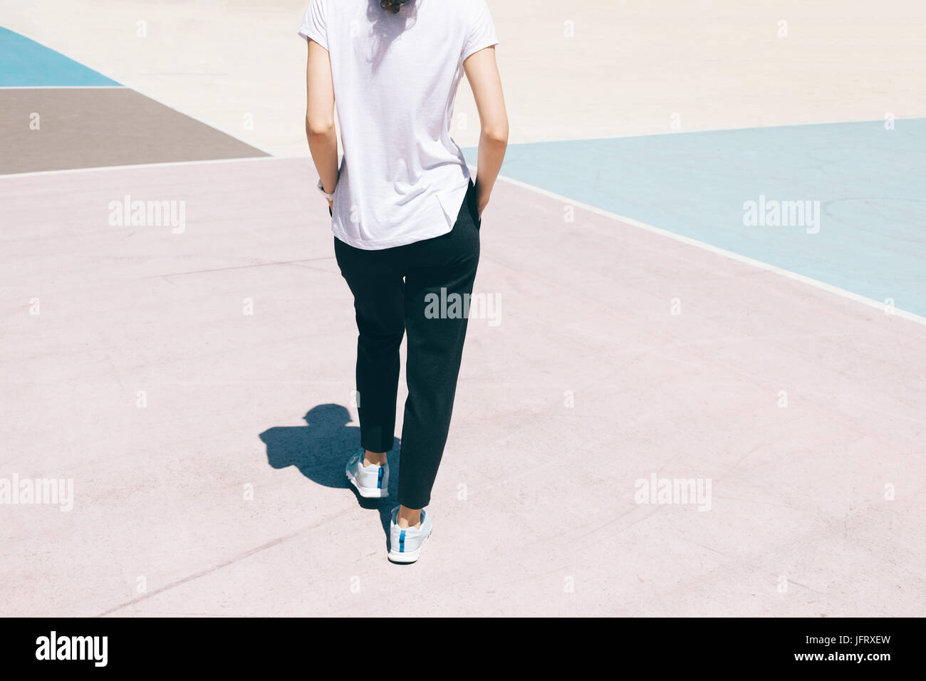 Portrait d'une jeune femme dans un pantalon de sport, T-shirt et chaussures de marche sur l'aire de jeux, vue de l'arrière Banque D'Images