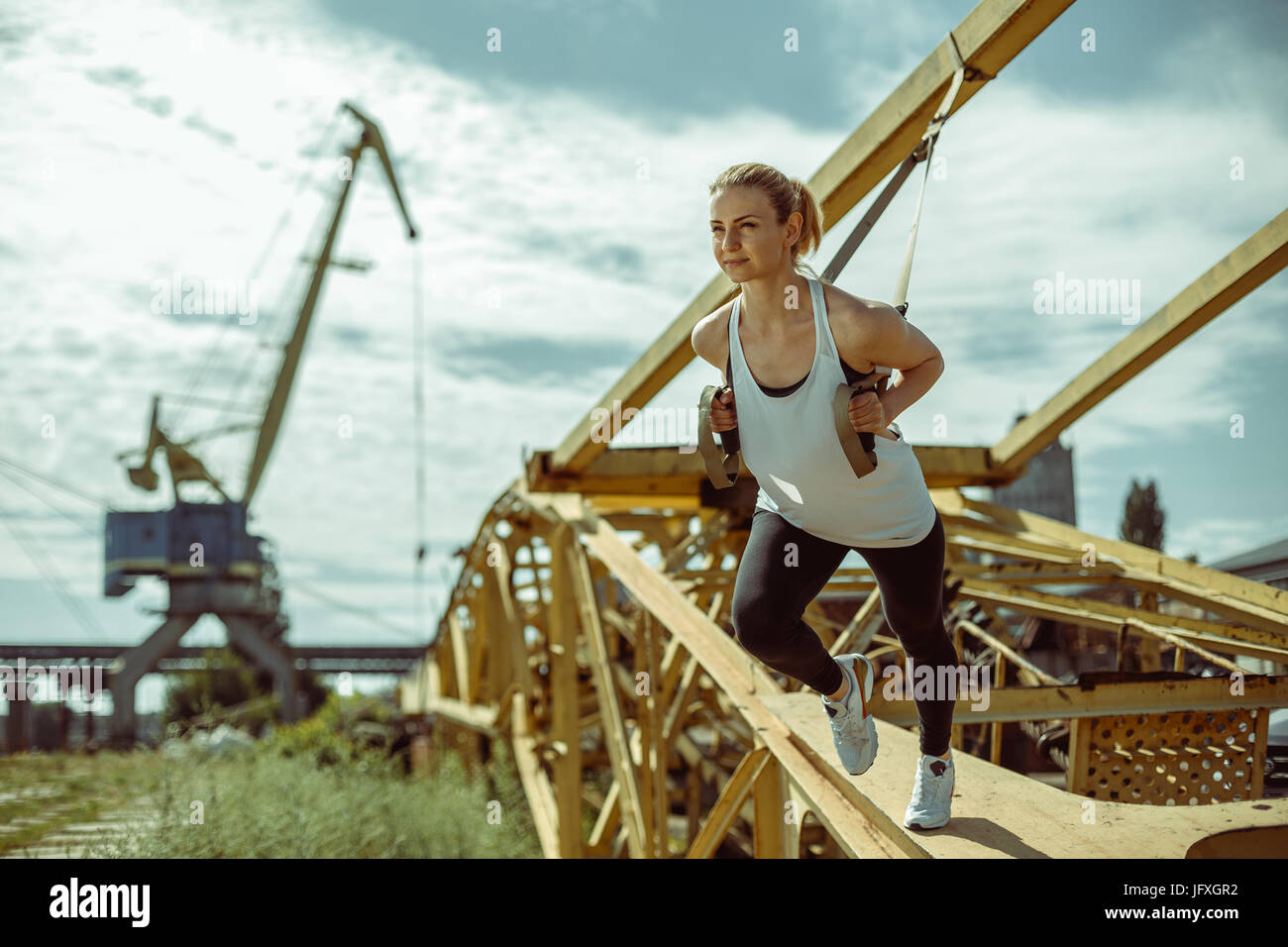 Cheerful woman exercising with suspension trainer outdoor Banque D'Images