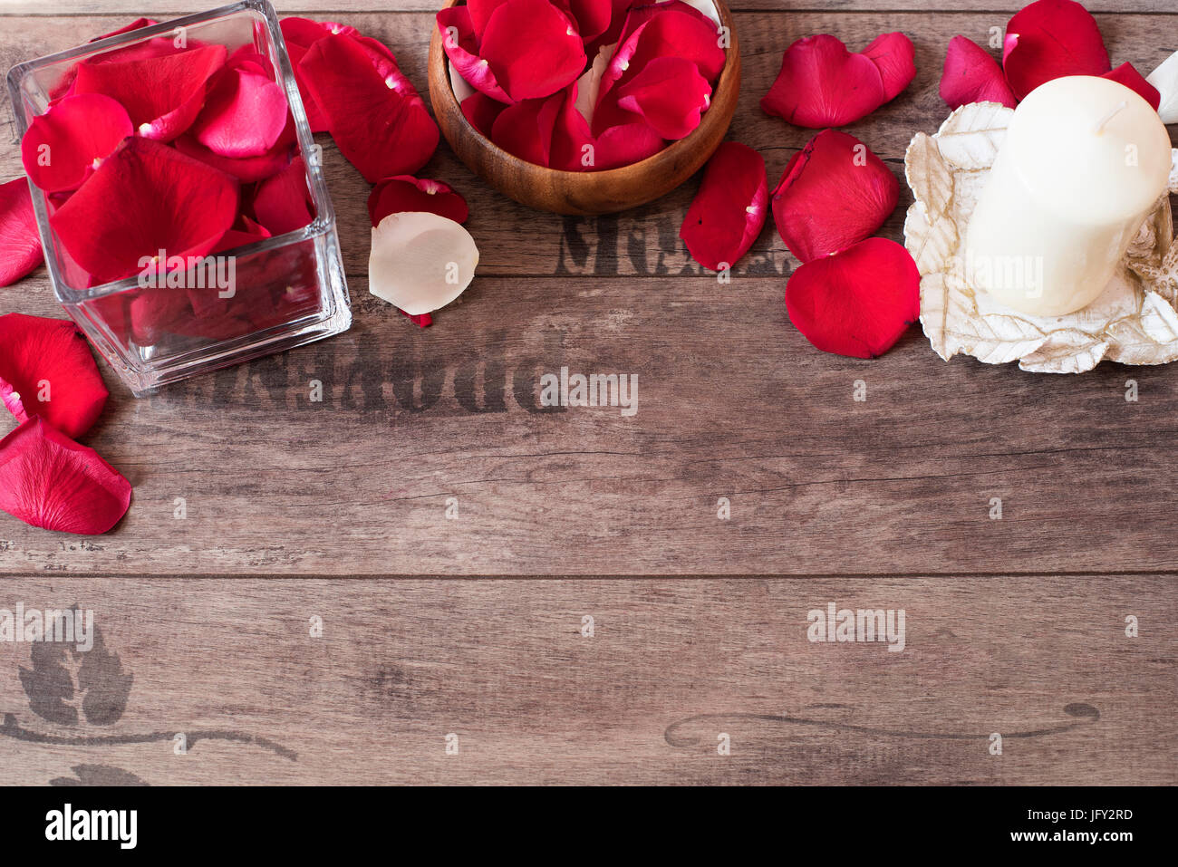 Vase en verre et bois bow remplie de pétales de rose rouge et blanc, blanc bougie vanille aromatiques. Fond de bois. Concept d'aromathérapie. Zone romantique Banque D'Images