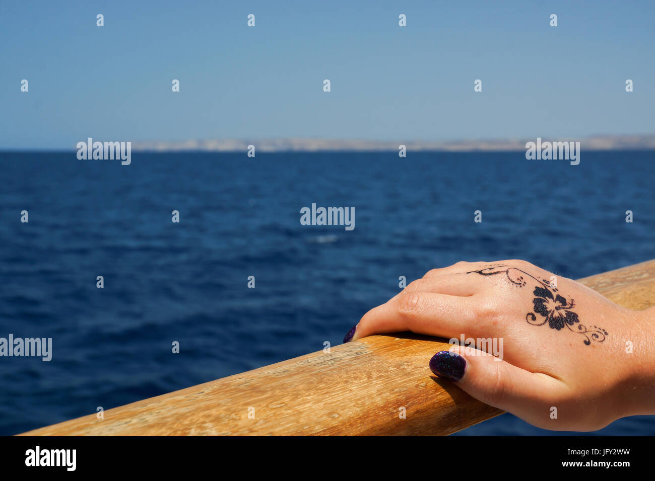 Une photographie d'une main féminine tenant la rampe d'un bateau dans la mer Méditerranée, Malte. Il y a une conception florale tatouage au henné sur le dos o Banque D'Images