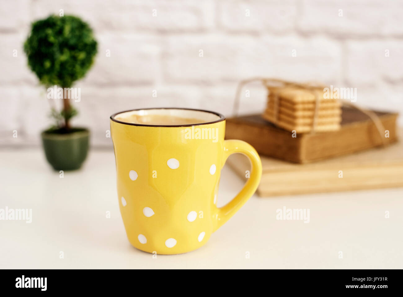 Tasse à café, cappuccino, latte, vieux livres, cookies et bonsai sur tableau blanc. Mur de briques grises. Concept de vie de loisirs. Lumière de fond rustique Banque D'Images