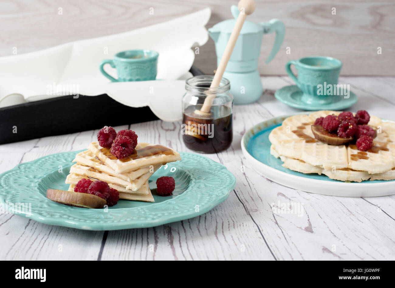 Gaufres en forme de coeur Belge soft avec les framboises et figues, recouvert de miel sur la plaque d'un bleu turquoise. Un plateau de café et bouilloire. Woo rustique Banque D'Images