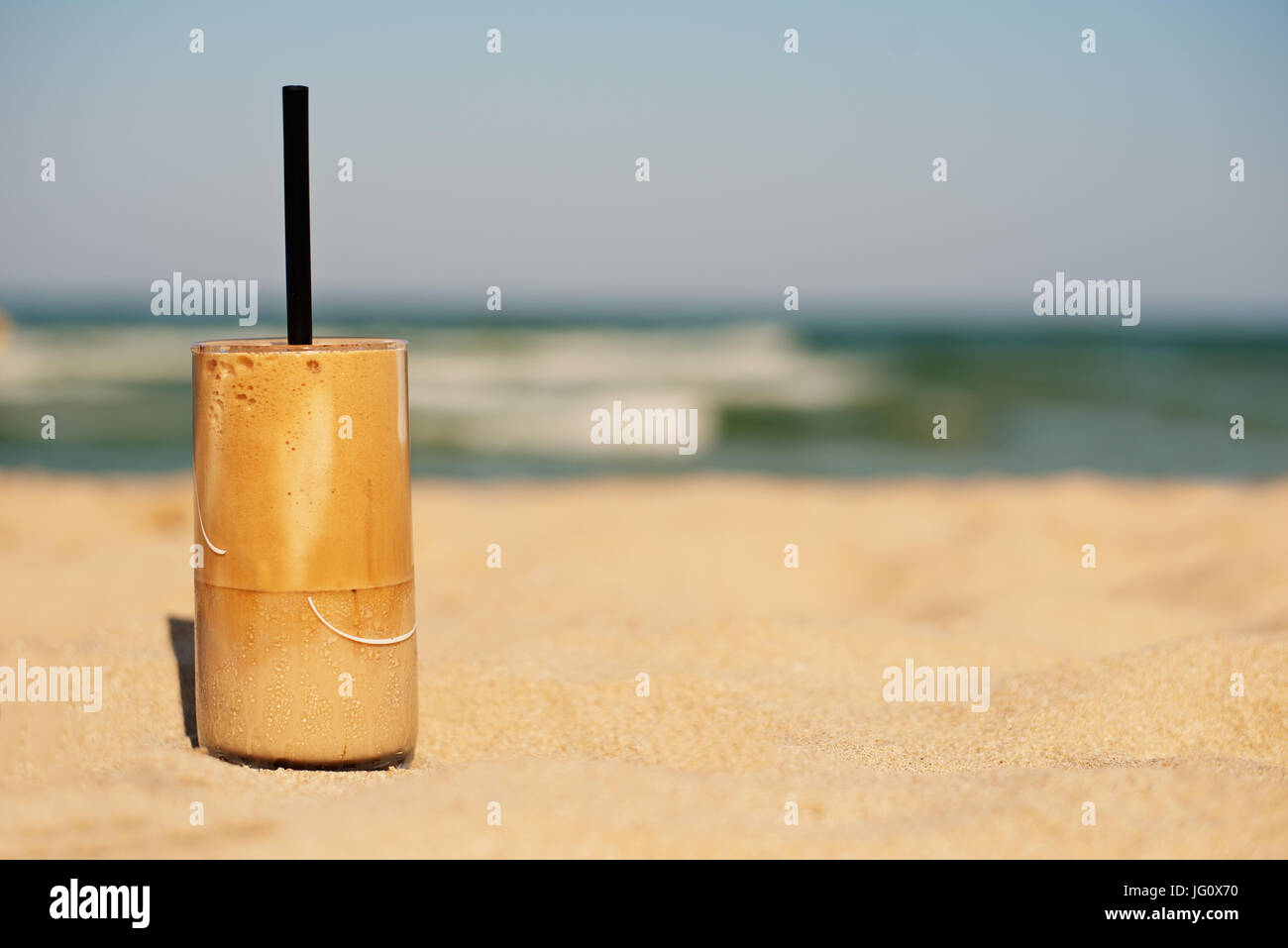 Frappe, glace café sur la plage. Café glacé en été (ou latte frappuccino, frappe) dans un grand verre sur fond de sable - bar de plage maison de vacances beverag froid Banque D'Images