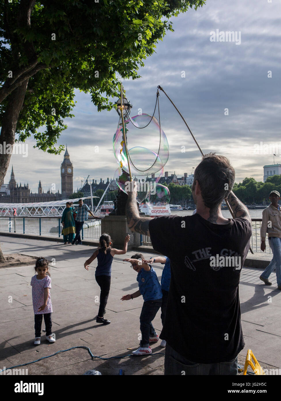 Un musicien ambulant de rue bulles souffle sur la rive sud de la Tamise à Londres avec les Chambres du Parlement et Big Ben en arrière-plan Banque D'Images