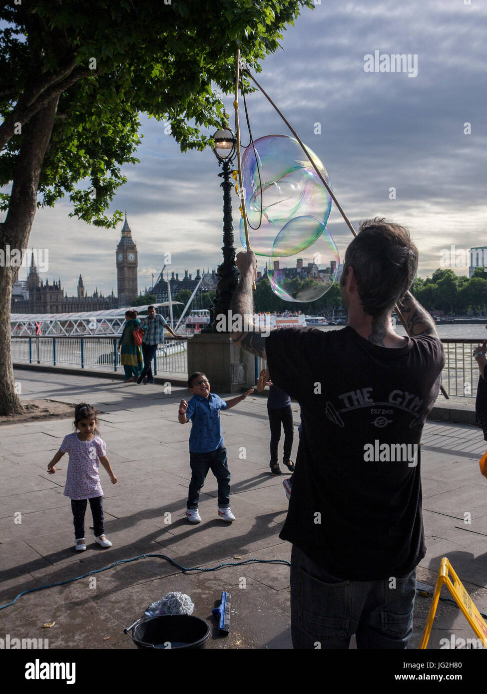 Un musicien ambulant de rue bulles souffle sur la rive sud de la Tamise à Londres avec les Chambres du Parlement et Big Ben en arrière-plan Banque D'Images