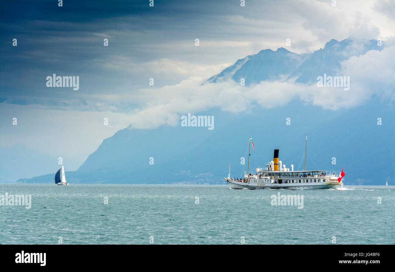 Magnifique bateau à aubes la Suisse croisière sur le lac Léman avec des montagnes et un voilier en arrière-plan, Suisse Banque D'Images