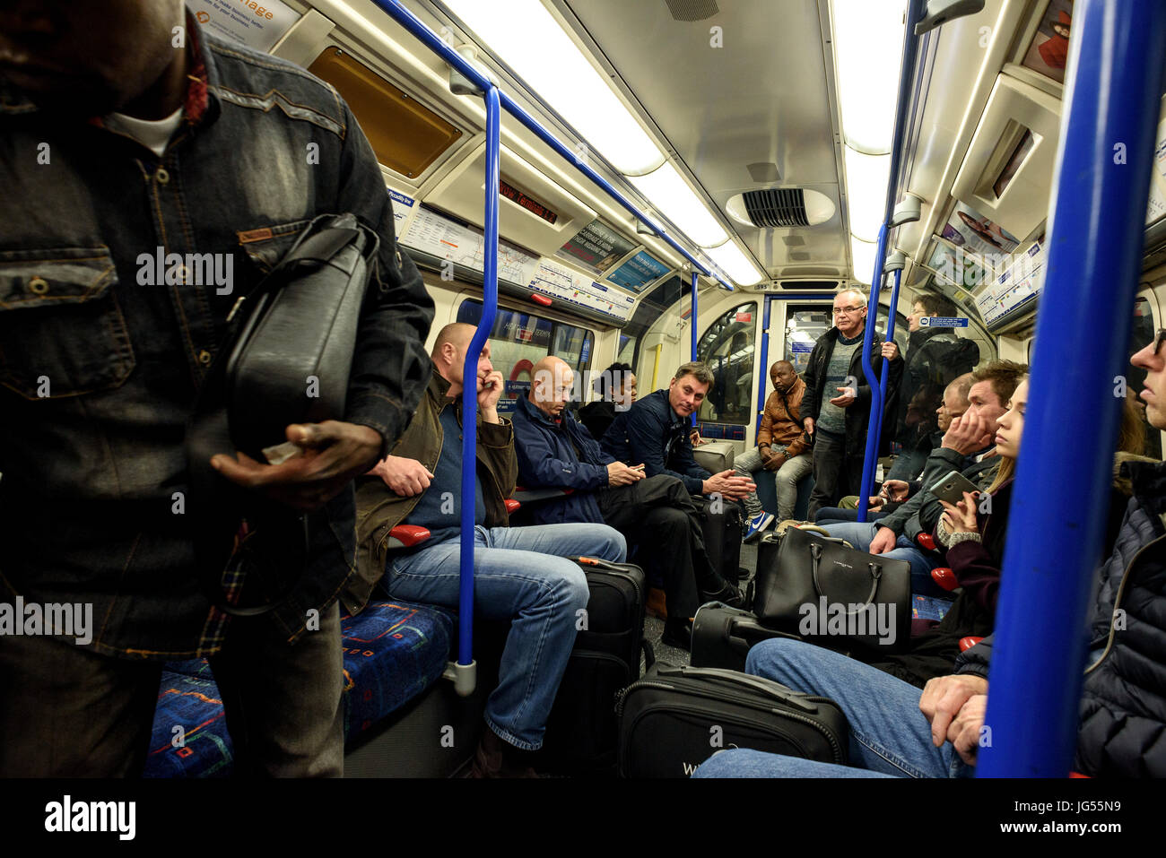 Diverses personnes mixtes sur une circonscription London Underground tube train dans leurs voitures à la fois la position assise et debout Banque D'Images