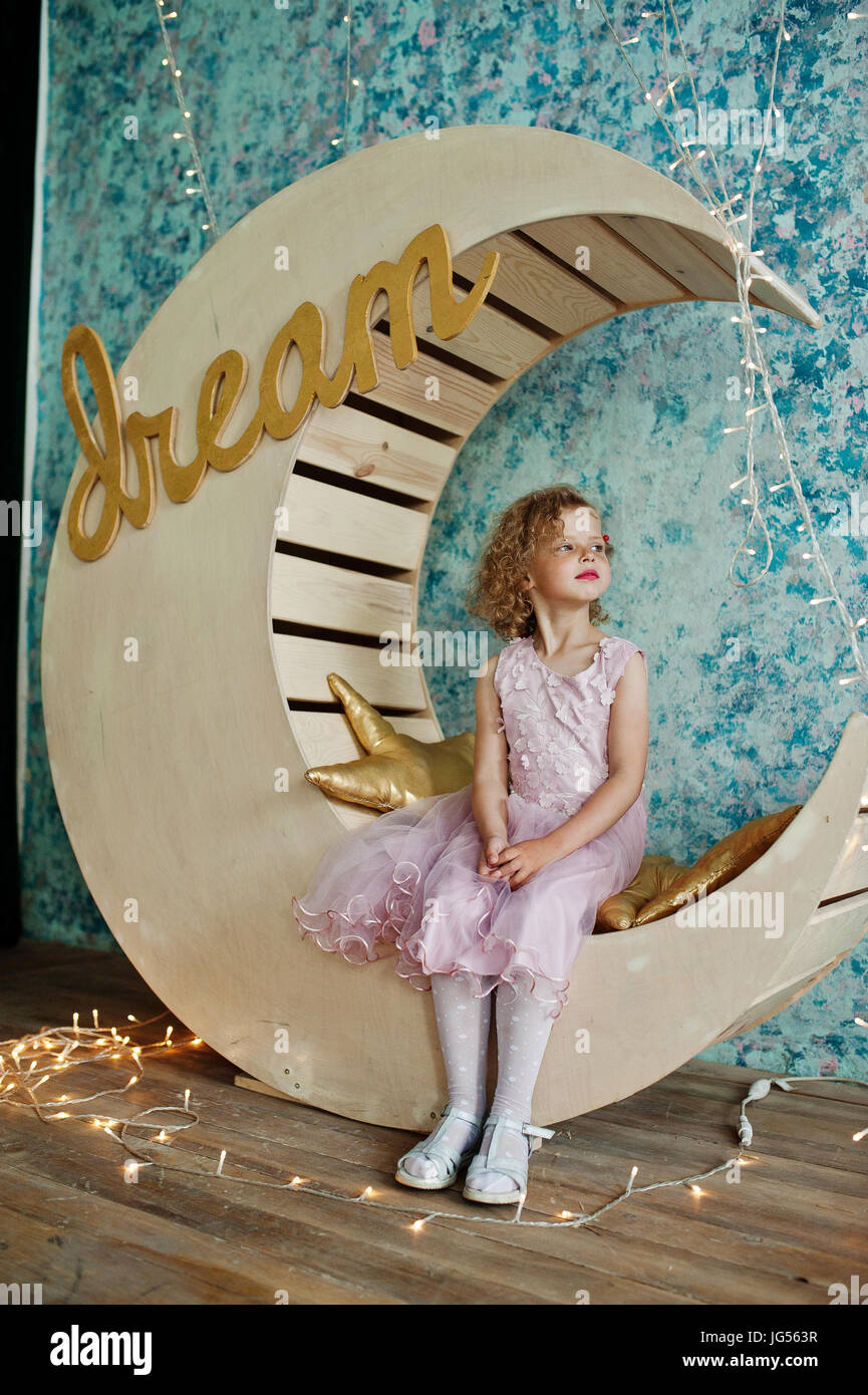 Belle petite fille dans une robe qui pose à côté de lune en bois avec  décoration golden star oreillers Photo Stock - Alamy