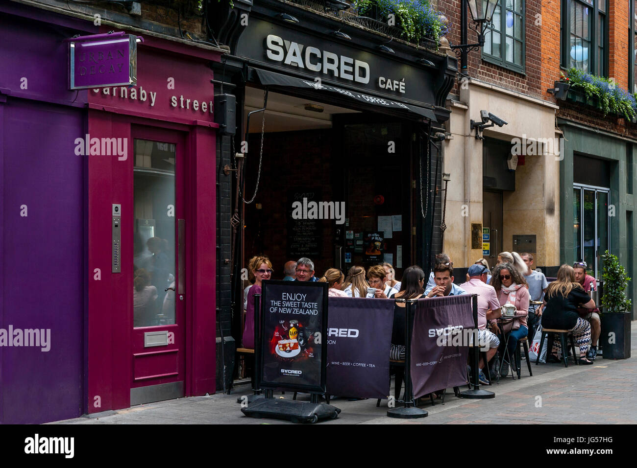 Les gens assis dehors le sacré Cafe, off Carnaby Street, London, UK Banque D'Images