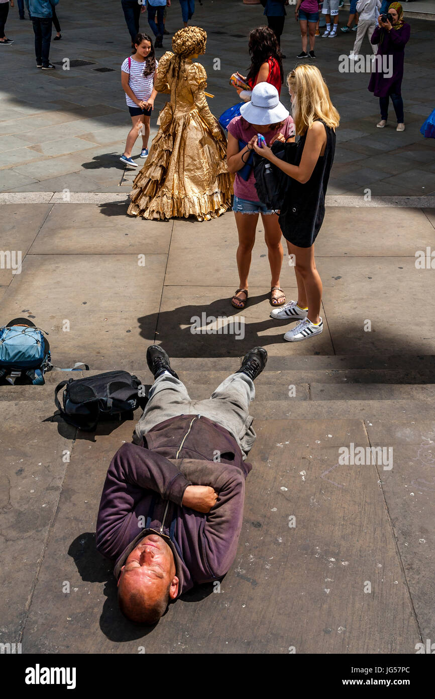 Un homme endormi sur les marches de la statue d'Eros, Piccadilly Circus, Londres, UK Banque D'Images