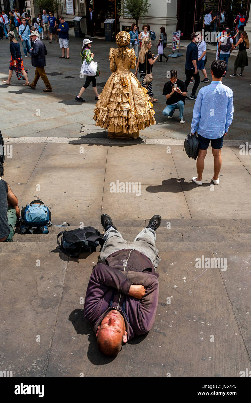 Un homme endormi sur les marches de la statue d'Eros, Piccadilly Circus, Londres, UK Banque D'Images