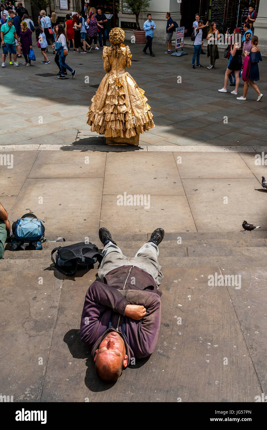 Un homme endormi sur les marches de la statue d'Eros, Piccadilly Circus, Londres, UK Banque D'Images