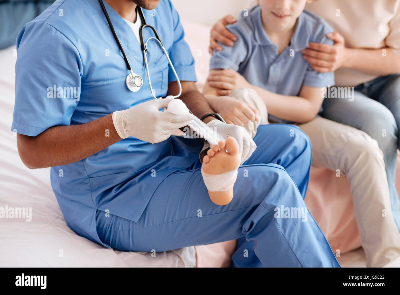Garçon joyeux donnant son pied pour bandage pansement Banque D'Images
