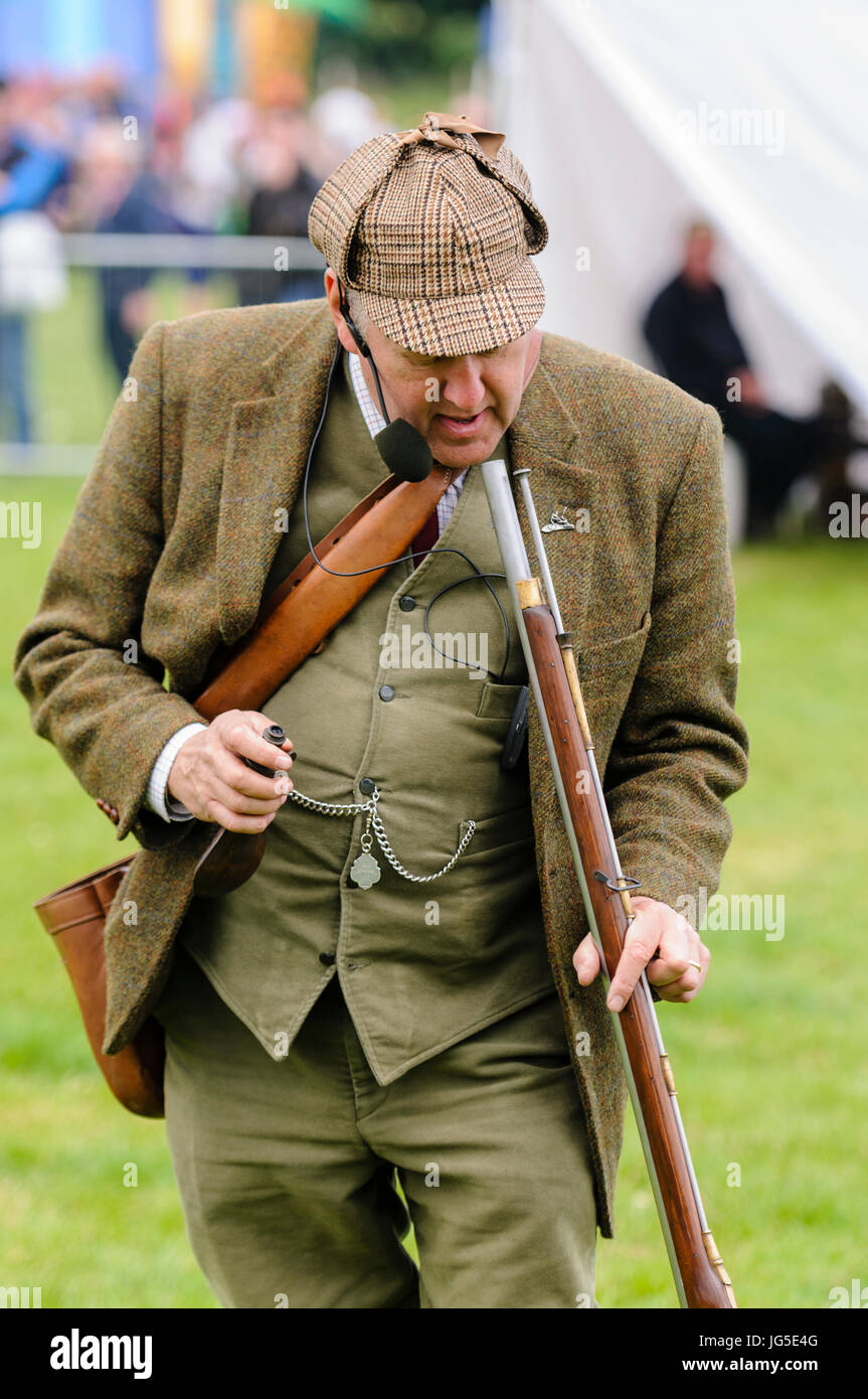 Un homme habillé en vert, veste en tweed Lovat irlandais chapeau  deerstalker, Gilet et pantalon, regarde vers le bas le canon de son fusil à  silex Photo Stock - Alamy