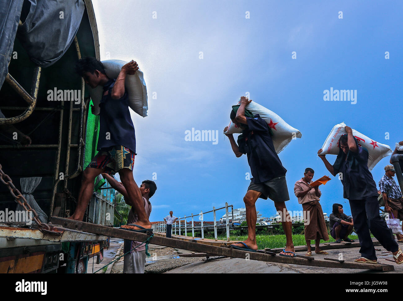 Le déchargement du fret provenant de travailleurs sur des bateaux en attente de camions à un quai à Yangon, Myanmar Banque D'Images