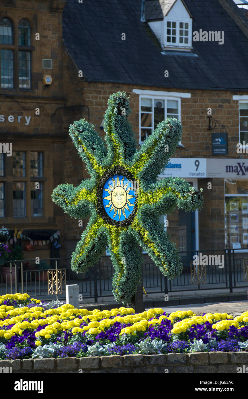 Symbole de soleil et de sculptures florales parterre coloré en face de Banbury Cross, tôt le matin la lumière. Oxfordshire, Angleterre Banque D'Images