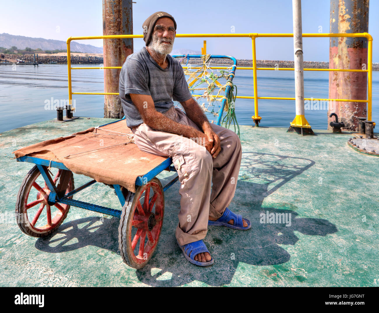 L'île d'Ormuz, en Hormozgan, Iran - 17 avril, 2017 personnes âgées : Un chargeur port iranien s'assied sur son chariot sur la jetée de l'île d'Ormuz. Banque D'Images
