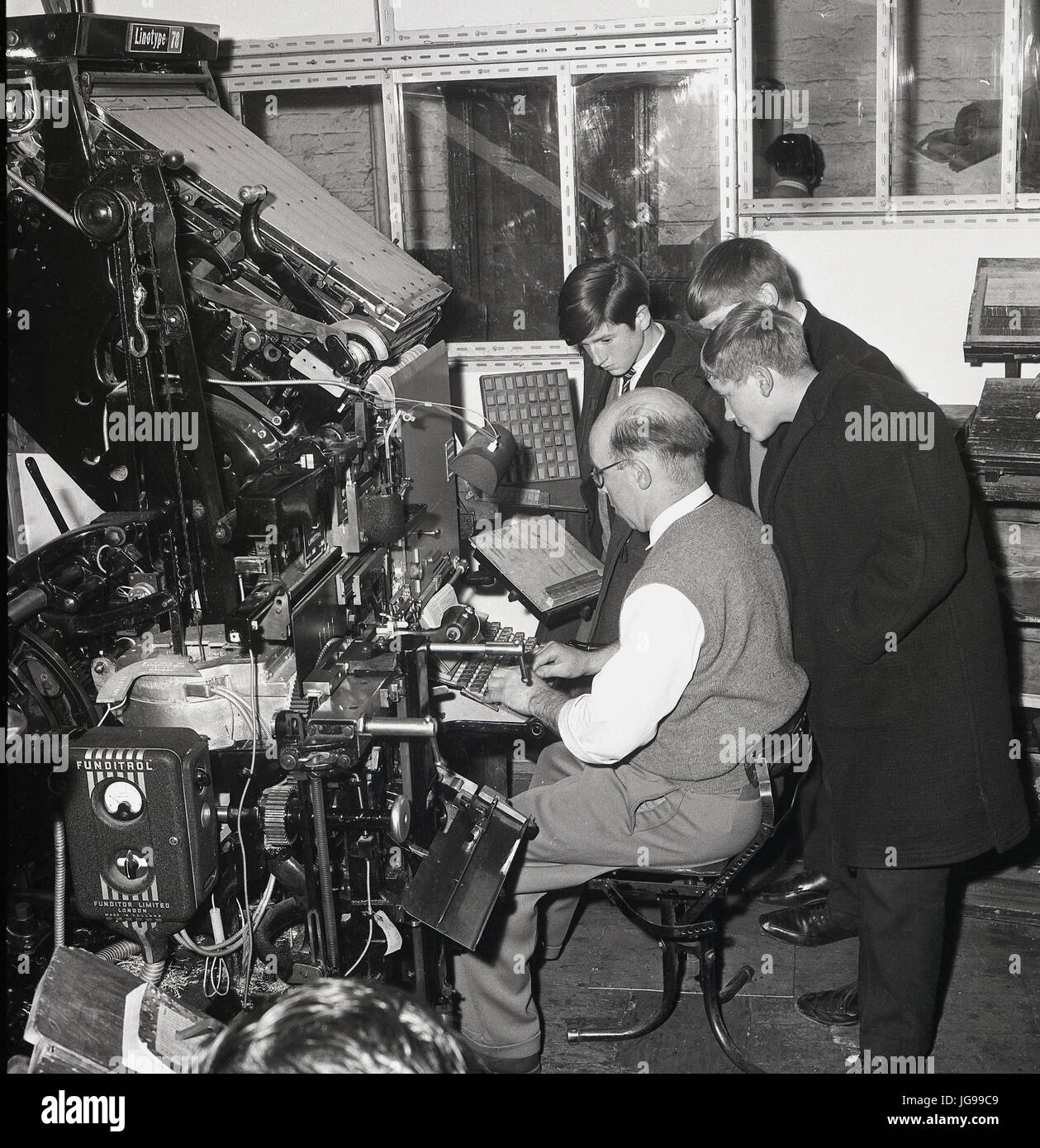 Dans les années 1960, trois écoliers regardent un composeur ou un composeur de journaux au travail lors d'une visite des presses du sud-est de Londres et du journal Kentish Mercury, Angleterre, Royaume-Uni. Banque D'Images