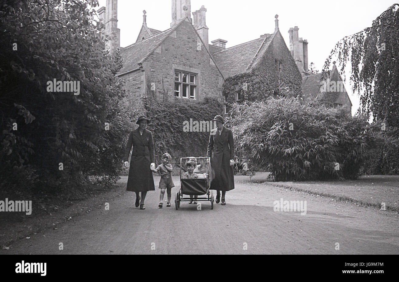1940, Angleterre, guerre, l'image montre l'extérieur de Stanstead Hall, maison de Lady Butler (Sydney Courtauld) épouse de Rab Butler, politiican conservateur et ministre, deux infirmières à pied un landau dans l'allée avec des enfants évacués de Hampstead garden Banlieue, Londres. Banque D'Images