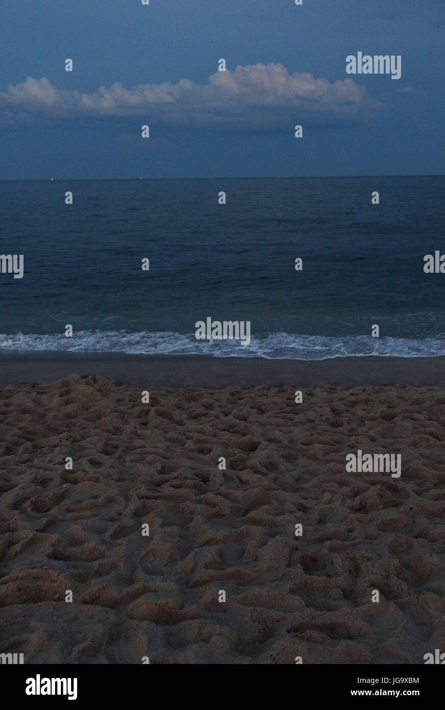 Twilight à la mer avec plage de sable avec des empreintes Banque D'Images