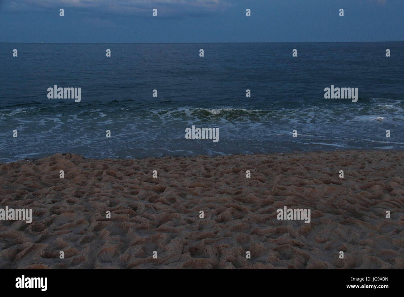 Twilight à la mer avec plage de sable avec des empreintes Banque D'Images